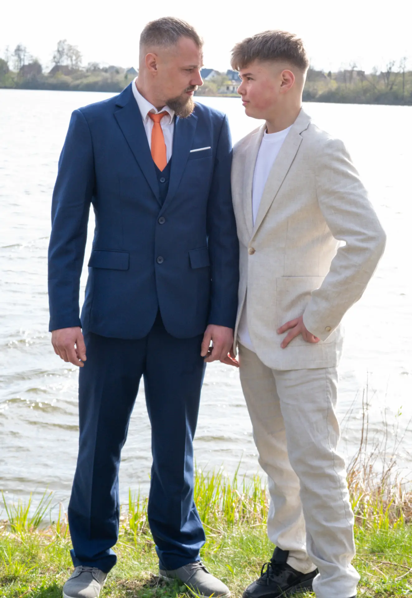 Vater und sein älterer Sohn im Portrait vor einem See bei einem Familien-Shooting.