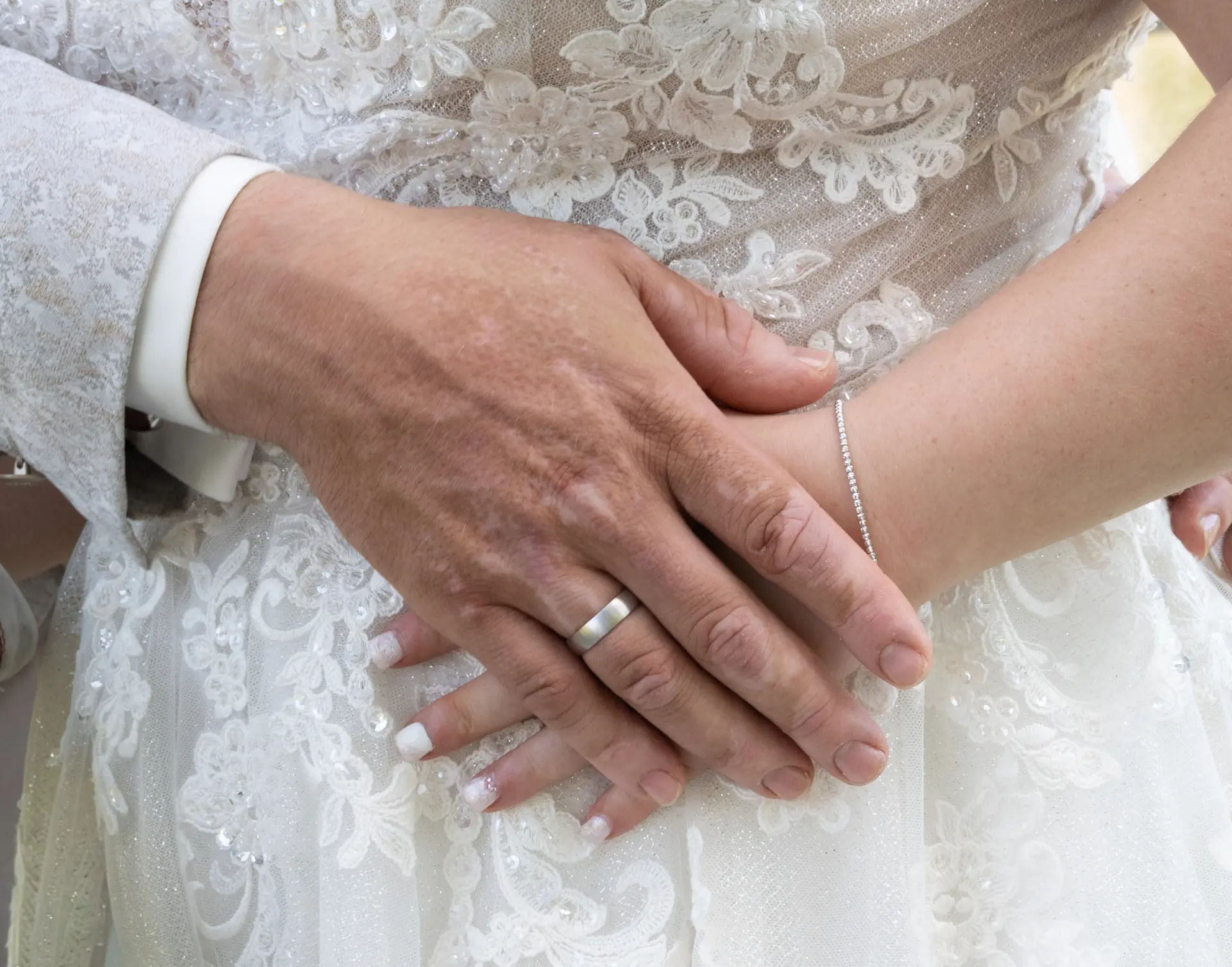 Nahaufnahme von einem Hochzeitspaar das glücklich Händchen hält.